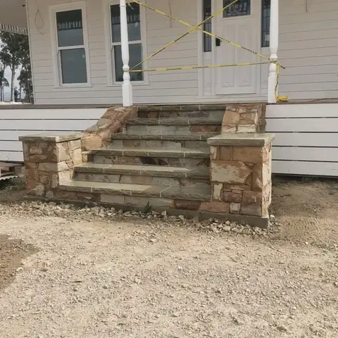 Stone steps with sandstone pillars leading to a house entrance