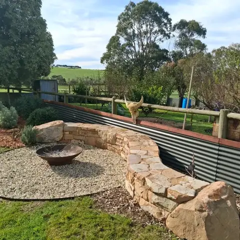 Curved stone wall around a gravel fire pit in a garden